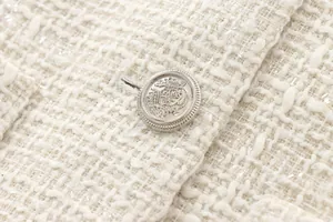 Close-up of elegant tweed jacket showing cream woven fabric and silver heraldic button