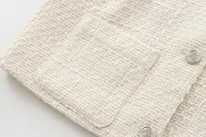 Detailed view of the luxury cream tweed fabric texture and ornate silver buttons.