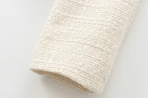Detailed close-up showing the woven texture and sleeve cuff of a cream tweed jacket.