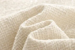Close-up of premium cream tweed fabric texture for elegant women's jackets.