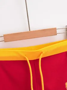 Detailopname van de gele geribbelde tailleband met trekkoord op rode retro shorts