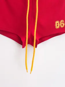 Detailopname van rode Amerikaanse retro hotpants met geel trekkoord en 06-opdruk