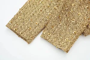 Detaillierte Ansicht glitzernder goldener Pailletten auf hochwertigem Tweed-Jackenstoff
