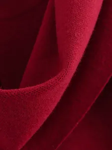 Nahaufnahme der tiefroten Strickwarentextur aus Wolle mit weichen Faserdetails.