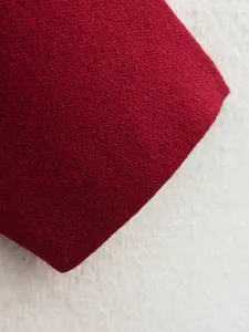 Nahaufnahme von tiefrotem Strickstoff mit weicher Wollstruktur und feiner Verarbeitung