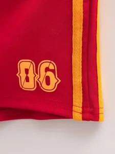 Detailopname van de rode vintage shorts met gele zijstrepen en nummer 06 printopdruk
