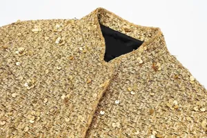 Nahaufnahme der goldfarbenen Paillettenjacke mit Details zu Kragen und Tweed-Struktur