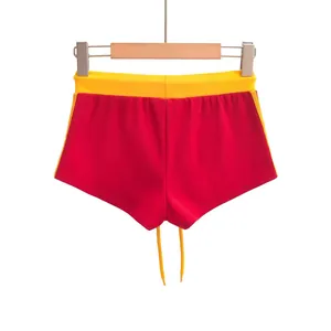 Opvallende rood-gele contrast sportbroek gepresenteerd op een houten kledinghanger