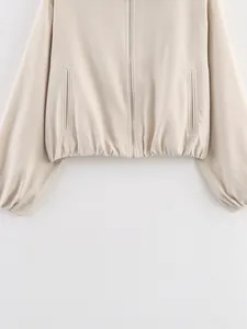 Detail van een beige bomberjack met rits, pofzoom, paspelzakken en elastische taille.