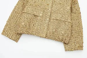Detaillierte Nahaufnahme einer goldfarbenen Pailletten-Tweedjacke mit Vordertaschen
