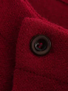 Detaillierte Makroaufnahme eines weinroten Strickmantels mit Textur und Knopf