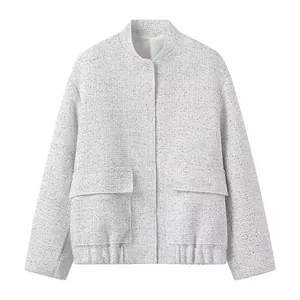 Detailansicht einer hellgrauen Tweedjacke mit goldenen Pailletten und großen Pattentaschen