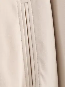 Gedetailleerde macroweergave van de fijne stiksels op een beige modieuze ritsjas
