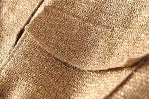 Nahaufnahme der goldfarbenen Paillettenstruktur an einer schicken Damenjacke mit Taschen