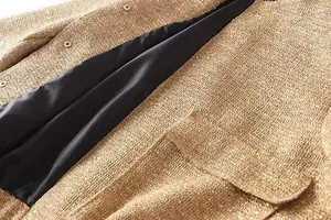 Nahaufnahme einer goldfarbenen Paillettenjacke mit strukturiertem Stoff und schwarzem Futter