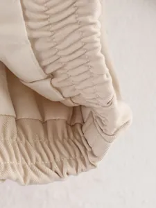 Gedetailleerde close-up van de elastische gesmokte zoom op een beige baseballjack