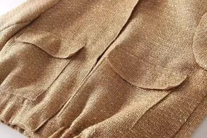Detailansicht der goldenen Tweed-Jacke mit glitzernden Pailletten und Pattentaschen