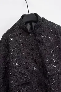 Nahaufnahme einer stylischen schwarzen Tweedjacke mit glänzenden Pailletten und Taschen.