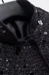 Detailansicht einer schwarzen Tweedjacke mit aufwendigen Paillettenblumen-Verzierungen.