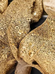 Detailaufnahme einer luxuriösen goldenen Pailletten-Tweed-Jacke mit elegantem Druckknopf