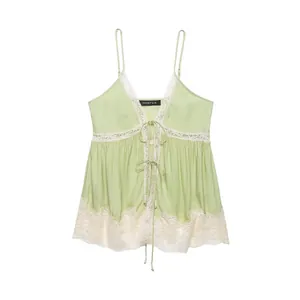 Macro detail of light green lace-trimmed camisole top with elegant tie-front bow details.
