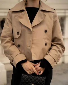 Close-up of beige double-breasted cropped trench coat with classic lapels and buttons.