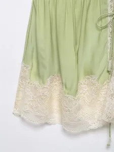 Close-up detail of a light green spring camisole top with elegant cream floral lace trim