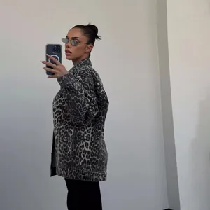 Trendy woman posing in a vintage leopard print denim jacket for a streetwear look