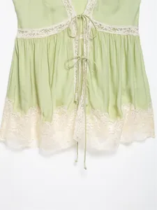 Close-up of sage green lace camisole top with delicate bow ties and floral trim details