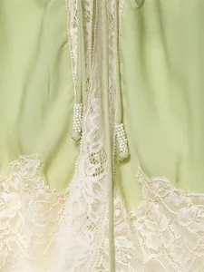 Detailed macro view of delicate cream lace trim and beaded drawstring on a green camisole