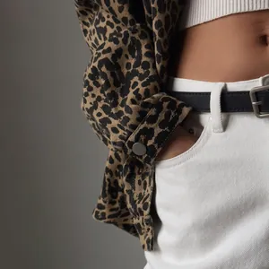 Macro detail view of American vintage leopard print denim jacket sleeve with metal button