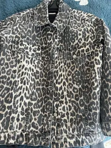 Detailed close-up view of vintage leopard print denim jacket with flap pockets and buttons