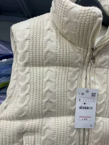 Detaillierte Nahaufnahme einer weißen Strickweste mit Zopfmuster und Markenetikett