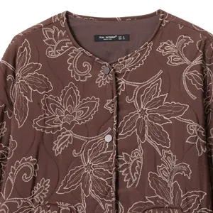 Detailansicht der braunen Steppjacke mit Blumenstickerei und ZEAL WOMAN-Etikett.