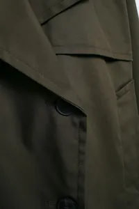 Close-up of olive green double-breasted jacket showing fabric texture and buttons