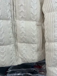 Detailansicht einer weiß gestrickten Steppjacke mit Zopfmuster, Textur und Reißverschluss