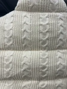 Detaillierte Textur einer weißen Strickjacke mit erhabenen Herzmustern.