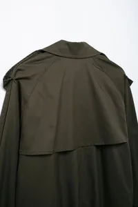 Close-up view of the back yoke and collar detail on a dark olive women's trench coat