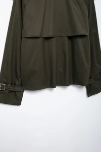 Macro detail view of back yoke and adjustable buckle straps on dark olive jacket