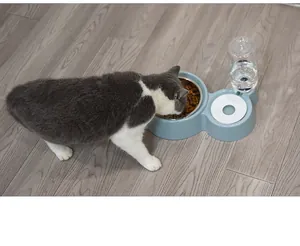 Escena real de un gato comiendo de un bebedero automático azul con cuenco de acero