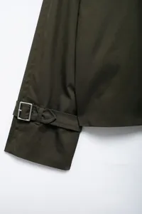 Detailed view of dark olive green jacket cuff with adjustable strap and metal buckle