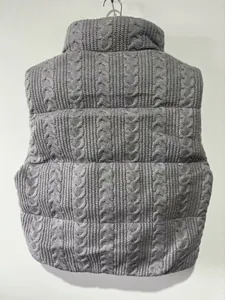 Detailansicht einer grauen Strick-Pufferweste mit einem warmen Zopfmuster-Design.