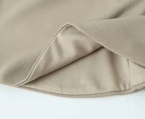 Makrodetail des beigen Strukturstoffs und des überlappenden Saumdesigns eines Schlauchoberteils