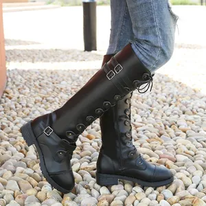 Botas altas negras para mujer con hebillas laterales y punta redonda sobre guijarros