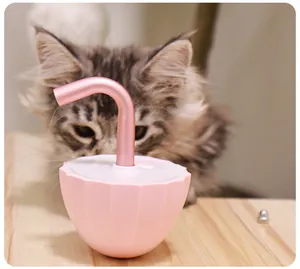 Macro view of a pink electric tumbler cat toy on a wood surface with a blurred cat