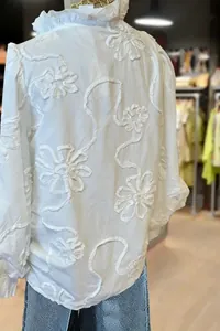 Close-up detail of white blouse featuring elegant floral embroidery and puff sleeve design