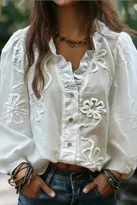 Close-up detail of white V-neck blouse featuring intricate floral embroidery and ruffle sleeves