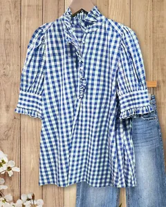 Dettaglio di una camicia vintage a scacchi bianchi e blu con maniche a sbuffo e volant