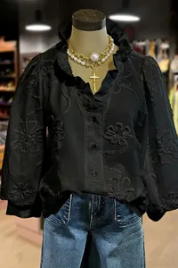 Close-up detail of a black V-neck blouse featuring floral embroidery and ruffle puff sleeves.