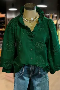 Detailed view of the intricate floral embroidery and ruffle trim on green puff sleeve blouse